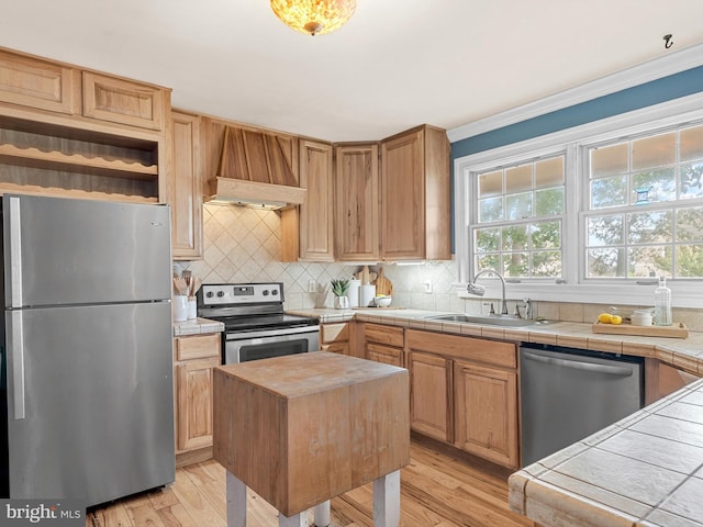 kitchen with tile countertops, tasteful backsplash, stainless steel appliances, sink, and light wood-type flooring