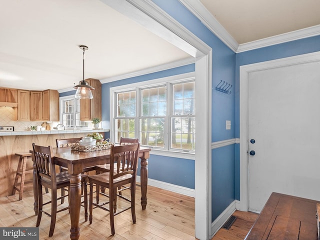 dining room with crown molding and light hardwood / wood-style flooring