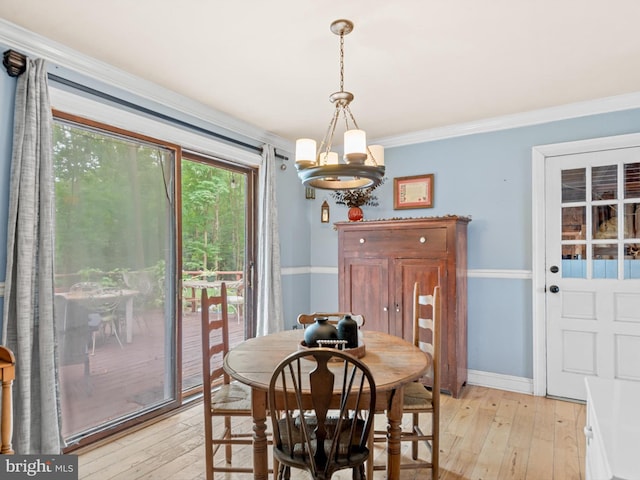 dining space featuring light wood-type flooring, a chandelier, and ornamental molding