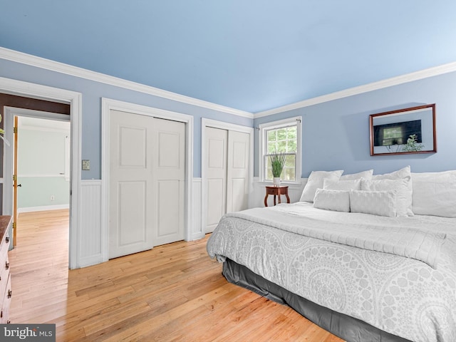 bedroom featuring crown molding, light hardwood / wood-style flooring, and two closets