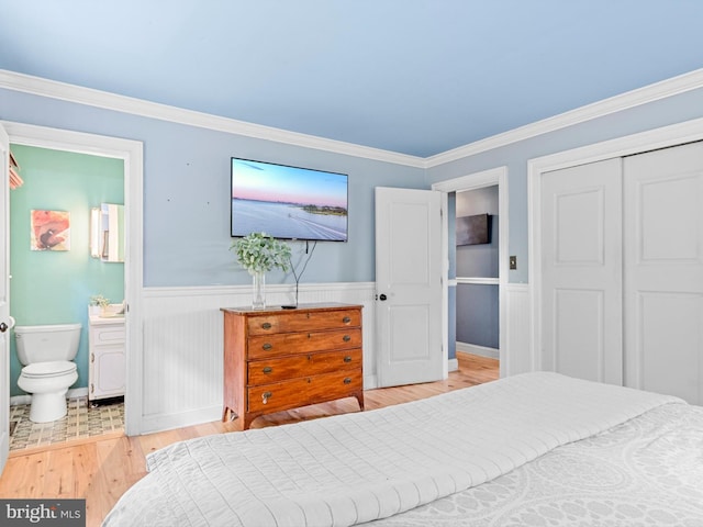 bedroom featuring light wood-type flooring, crown molding, connected bathroom, and a closet