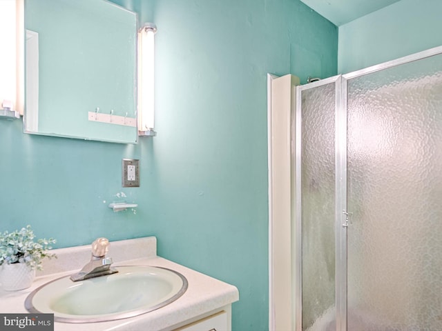 bathroom featuring a shower with door and vanity