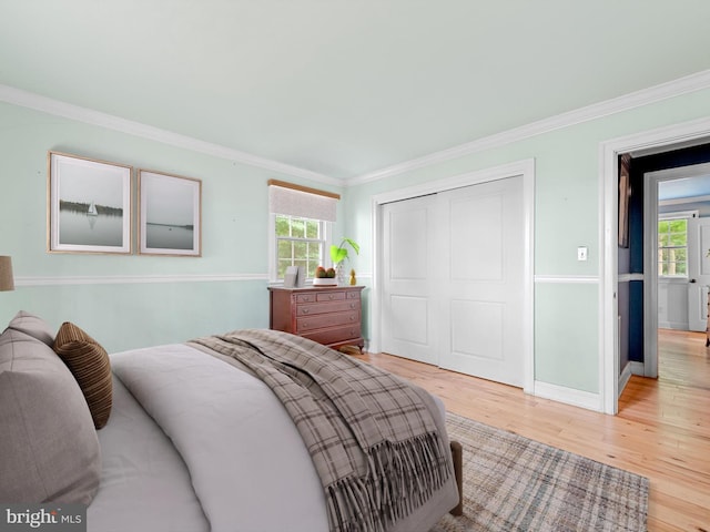 bedroom featuring crown molding, a closet, multiple windows, and light hardwood / wood-style floors