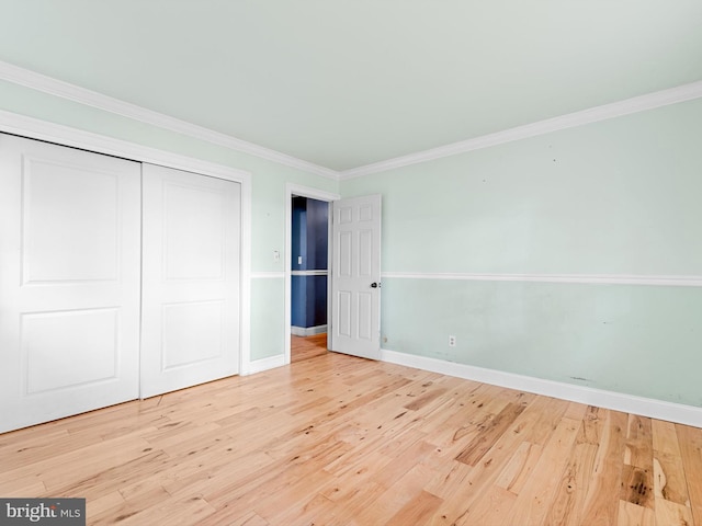 unfurnished bedroom featuring crown molding, a closet, and light hardwood / wood-style floors