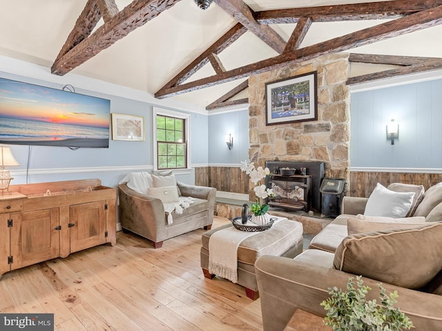 living room with a fireplace, light wood-type flooring, and vaulted ceiling with beams