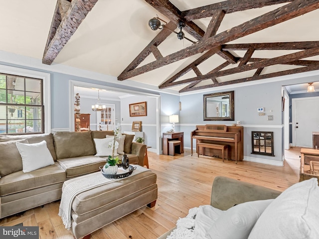 living room featuring an inviting chandelier, vaulted ceiling with beams, and light hardwood / wood-style floors