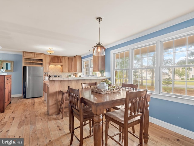 dining area featuring ornamental molding and light hardwood / wood-style floors