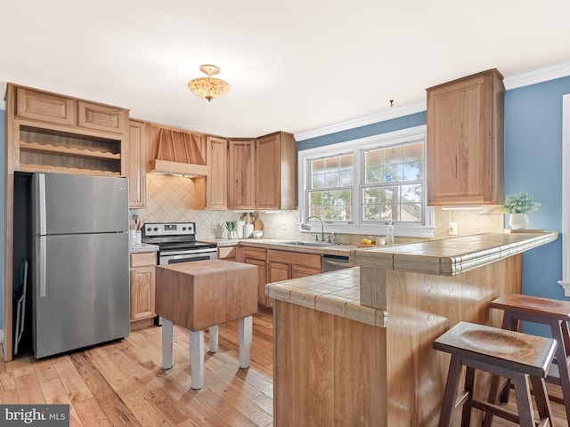 kitchen with a kitchen bar, kitchen peninsula, sink, and appliances with stainless steel finishes