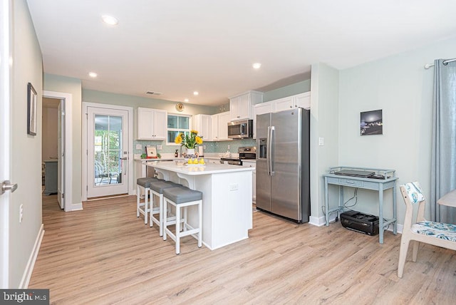 kitchen with light wood-type flooring, a center island, stainless steel appliances, and white cabinetry