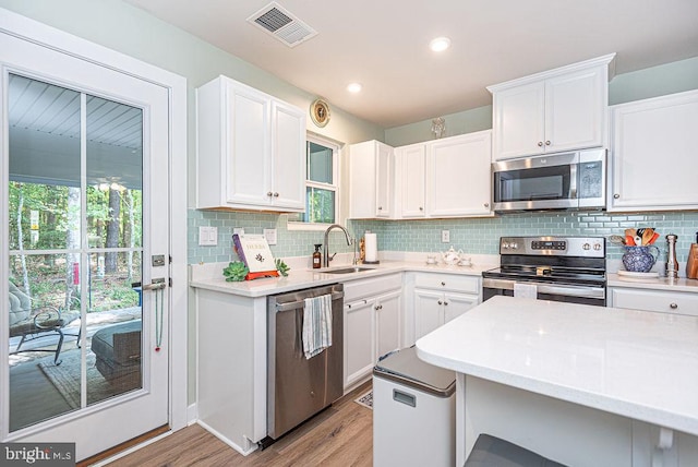 kitchen featuring sink, appliances with stainless steel finishes, white cabinetry, and light hardwood / wood-style floors