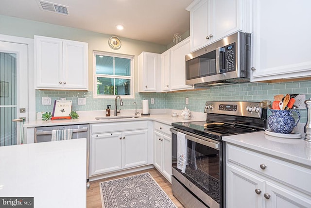 kitchen with light wood-type flooring, stainless steel appliances, white cabinetry, and sink