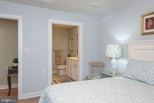 bedroom with ensuite bathroom and light hardwood / wood-style floors