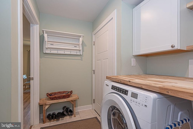 laundry room featuring washer / dryer, cabinets, and light tile patterned floors