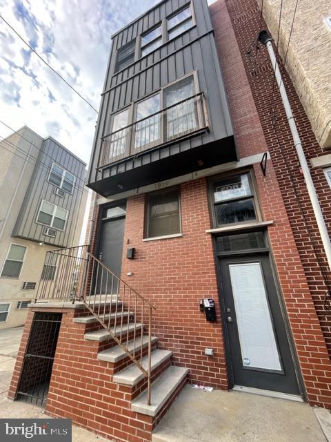 view of front of house featuring mansard roof and brick siding