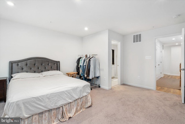 bedroom with light colored carpet and ensuite bathroom