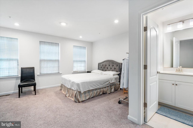 bedroom featuring sink, light carpet, and ensuite bathroom