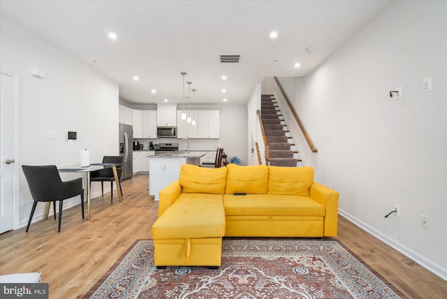 living room featuring sink and light hardwood / wood-style flooring