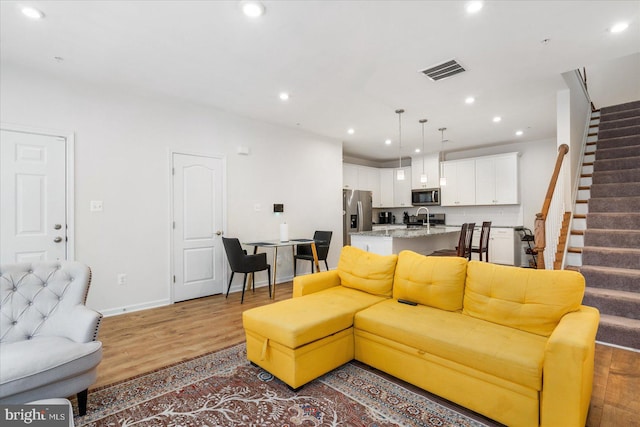 living room with light hardwood / wood-style floors and sink