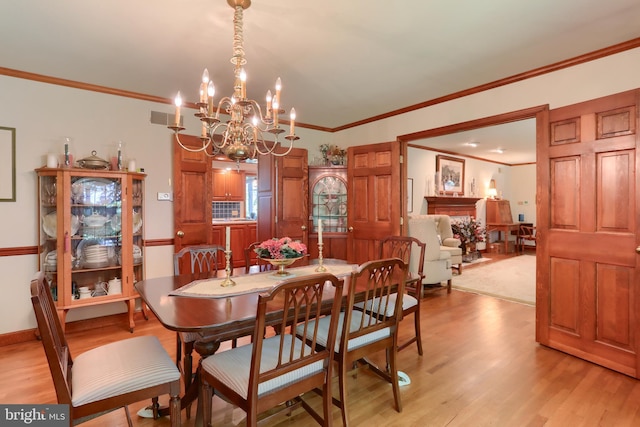 dining room featuring light wood-style floors, visible vents, crown molding, and baseboards