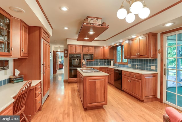 kitchen with light countertops, a center island, black appliances, glass insert cabinets, and pendant lighting