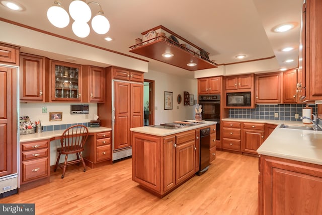 kitchen featuring light countertops, hanging light fixtures, built in study area, a center island, and black appliances