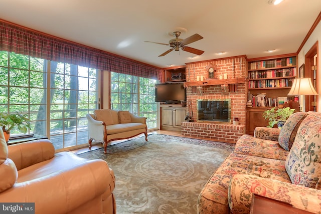 living room with ornamental molding, a brick fireplace, a wealth of natural light, and a ceiling fan