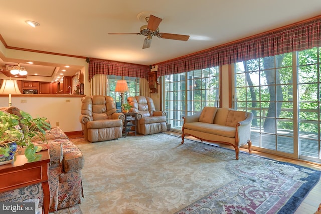 living room featuring baseboards, crown molding, and ceiling fan with notable chandelier