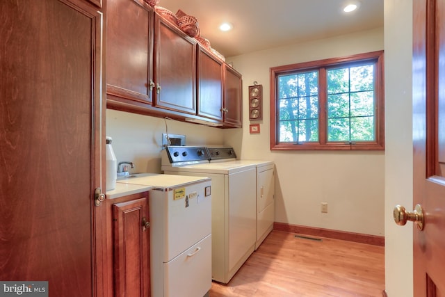 washroom featuring cabinet space, visible vents, light wood-style floors, washer and dryer, and baseboards