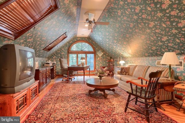 living room featuring lofted ceiling, wallpapered walls, and light wood-style flooring