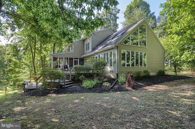 rear view of property featuring a sunroom and a wooden deck