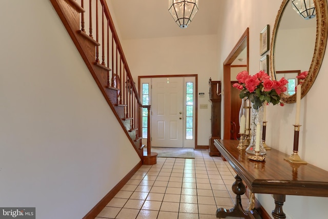 entrance foyer with a high ceiling, stairs, baseboards, and light tile patterned flooring