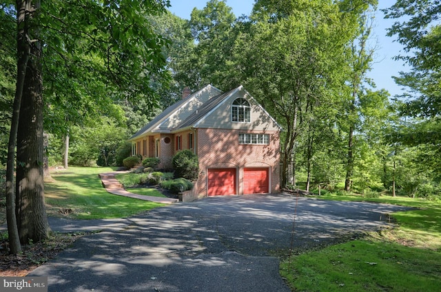 view of home's exterior with driveway, a chimney, an attached garage, a yard, and brick siding