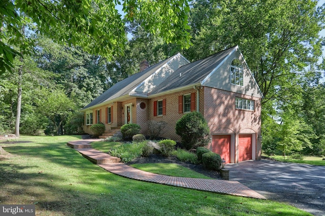 view of side of home featuring a chimney, aphalt driveway, an attached garage, a yard, and brick siding