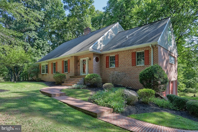 view of front of property with a front yard, a chimney, and brick siding