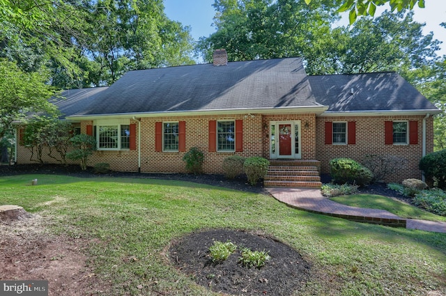 single story home featuring roof with shingles, brick siding, a chimney, and a front yard