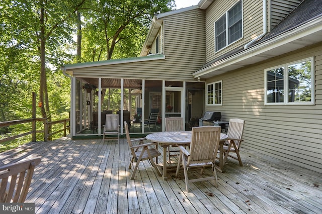 wooden deck with a sunroom, grilling area, and outdoor dining area