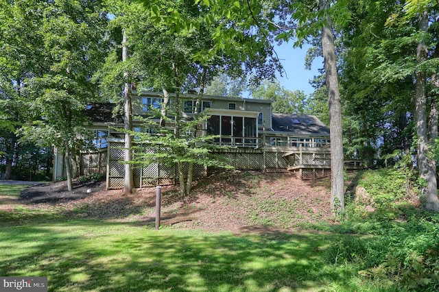 back of property featuring a sunroom, a deck, and a lawn