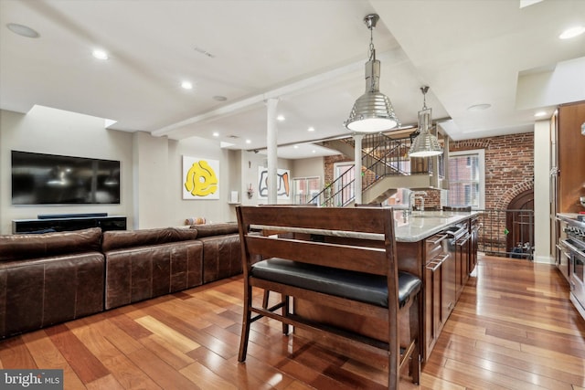 kitchen featuring light hardwood / wood-style flooring, brick wall, light stone countertops, a fireplace, and a center island with sink