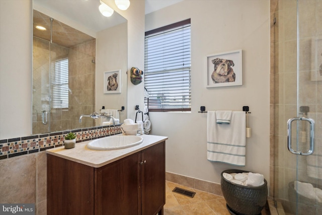 bathroom with a shower with door, vanity, and tile patterned floors