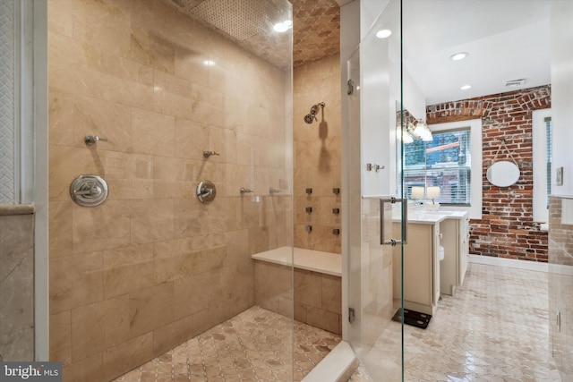 bathroom with a tile shower, brick wall, and vanity