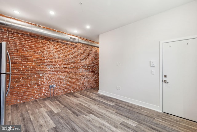 unfurnished room with brick wall and hardwood / wood-style flooring