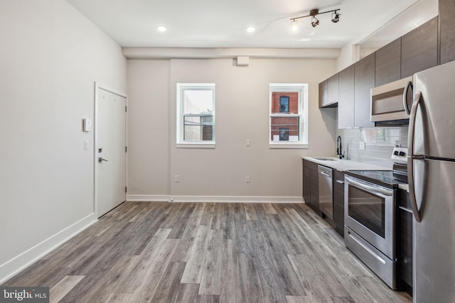 kitchen featuring sink, stainless steel appliances, track lighting, and wood-type flooring