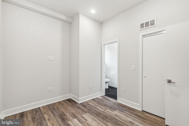 unfurnished bedroom with ensuite bath and hardwood / wood-style floors