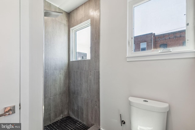 bathroom with a tile shower and toilet