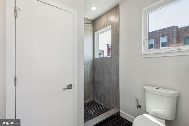 bathroom with a tile shower and toilet