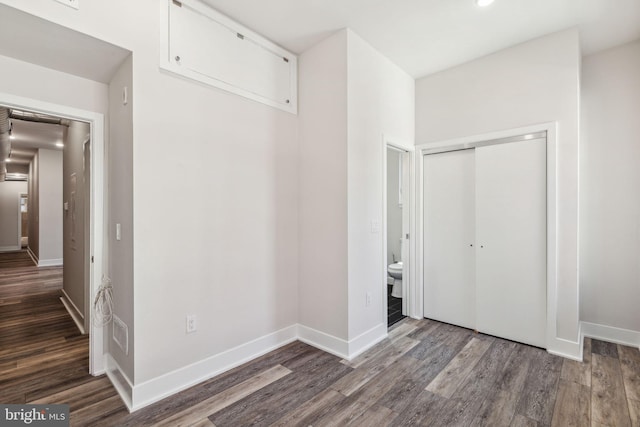 unfurnished bedroom with hardwood / wood-style flooring, a closet, and ensuite bath