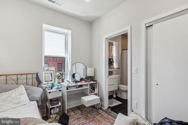 bedroom featuring ensuite bath and hardwood / wood-style floors