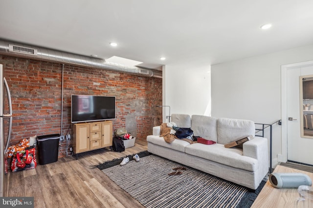 living room with brick wall and hardwood / wood-style flooring