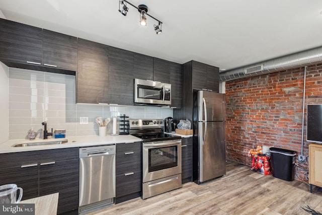 kitchen featuring appliances with stainless steel finishes, sink, light hardwood / wood-style flooring, and decorative backsplash