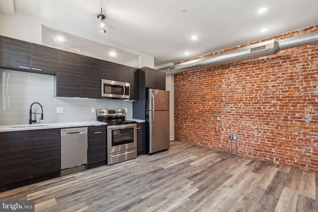 kitchen with light wood-type flooring, appliances with stainless steel finishes, sink, and decorative backsplash